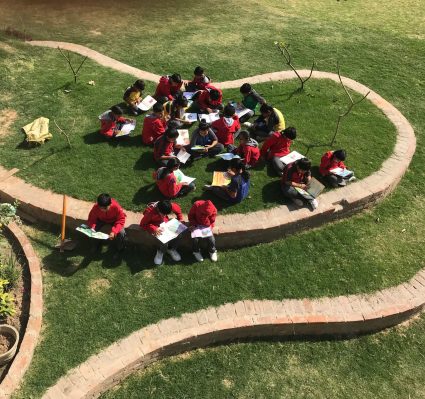 Students Reading Books Outdoors on School Lawn